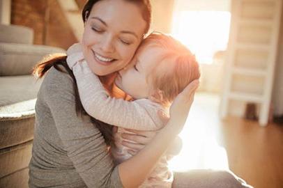 A young mom holding her baby and smiling